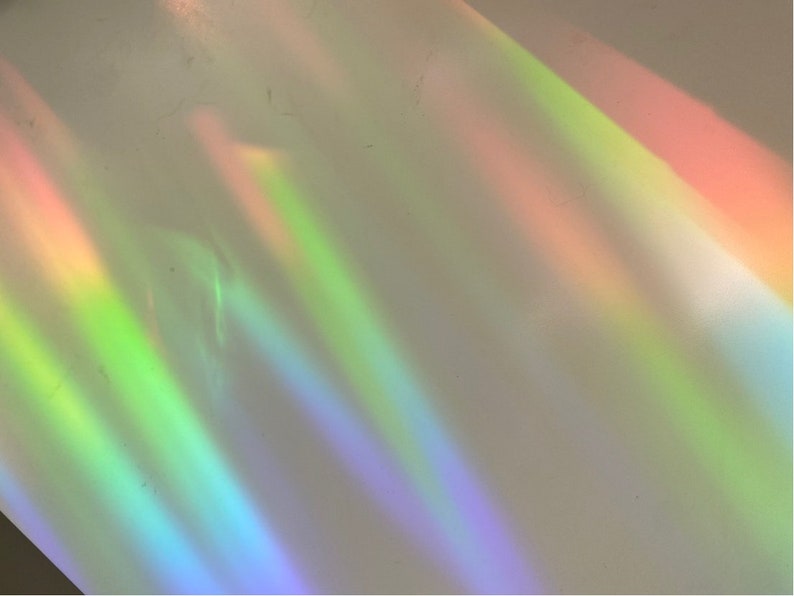 May include: Abstract background with iridescent rainbow colors in shades of green, blue, purple, and orange. The colors are blurred and appear to be light shining through a prism.