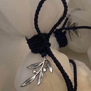 May include: A white tulle bag tied with a navy blue satin ribbon and a silver olive branch charm.