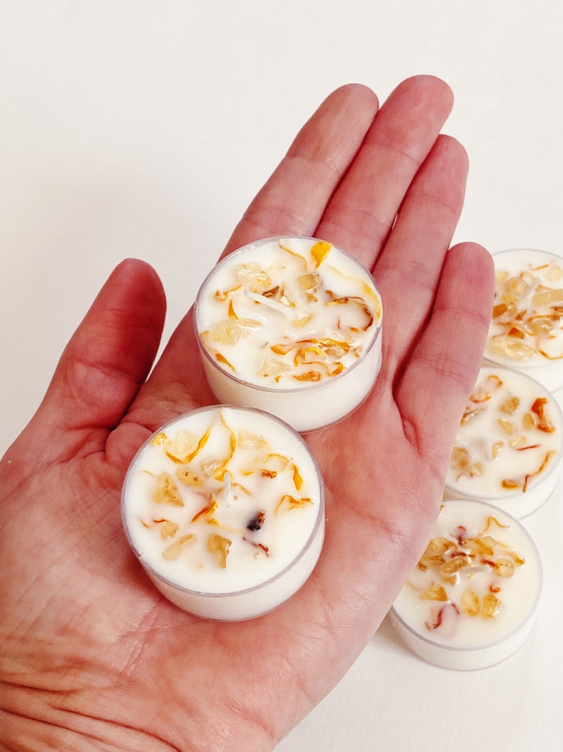 Peut inclure: Un ensemble de quatre bougies chauffe-plat blanches avec des p&eacute;tales de fleurs s&eacute;ch&eacute;es incrust&eacute;s dans la cire. Les bougies sont dans un r&eacute;cipient en plastique transparent.
