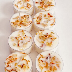 Peut inclure: Huit bougies chauffe-plat blanches dans des contenants transparents. Chaque bougie a une base de cire blanche avec de petits morceaux d'&eacute;corce d'orange s&eacute;ch&eacute;e et une m&egrave;che blanche.
