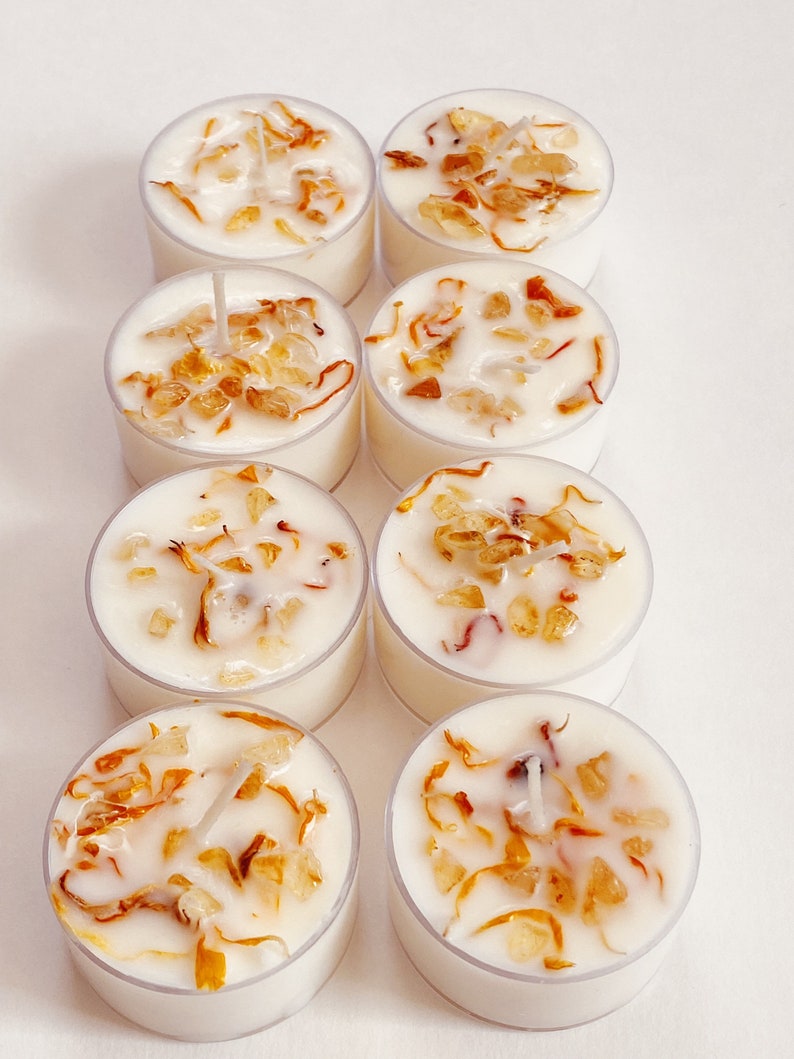 Peut inclure: Huit bougies chauffe-plat blanches dans des contenants transparents. Chaque bougie a une base de cire blanche avec de petits morceaux d'&eacute;corce d'orange s&eacute;ch&eacute;e et une m&egrave;che blanche.