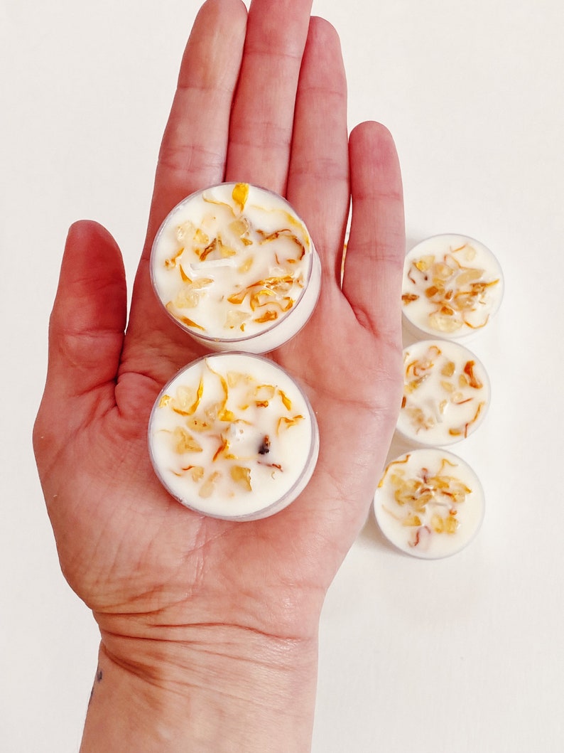 Peut inclure: Cinq petites bougies chauffe-plat blanches dans des contenants en plastique transparent. Les bougies sont remplies de cire blanche et contiennent de petits morceaux d'&eacute;corce d'orange s&eacute;ch&eacute;e incorpor&eacute;s &agrave; la cire.