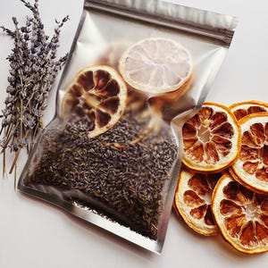 May include: A clear, resealable plastic pouch filled with dried lavender buds and two dried citrus slices. Beside the pouch are several additional dried citrus slices and a small bundle of dried lavender stems with purple flowers.