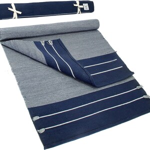 May include: A navy blue and white striped cotton rug with fringe tassels. The rug is rolled up and tied with a white ribbon.