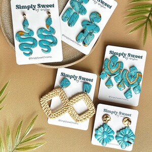 Könnte beinhalten: Eine Auswahl handgefertigter Ohrringe in Türkis und Gold, mit Designs wie Schlangen, geometrischen Formen und Blumen. Die Ohrringe werden auf weißen Karten mit dem Text "Simply Sweet by christina" präsentiert.