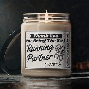 May include: A soy wax candle with a white label that reads "Thank You For Being The Best Running Partner Ever". The label also features a pair of running shoes. The candle is 9 ounces and has a burn time of 50 hours.