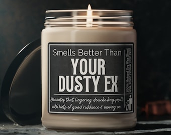 May include: A brown soy wax candle in a glass jar with a black label that reads "Smells Better Than Your Dusty Ex". The label also includes the text "Alleviates that lingering douche bag smell with hints of good riddance & moving on" and "100% Natural Soy Wax Blend NON-TOXIC | VEGAN | DYE FREE".