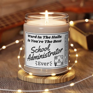 May include: A brown candle with a white label that reads "Word In The Halls Is You're The Best School Administrator Ever". The candle is sitting on a wooden coaster.