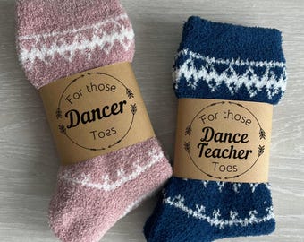 May include: Two pairs of fuzzy socks with decorative labels. The pink socks have a label that says "For those Dancer Toes". The blue socks have a label that says "For those Dance Teacher Toes".