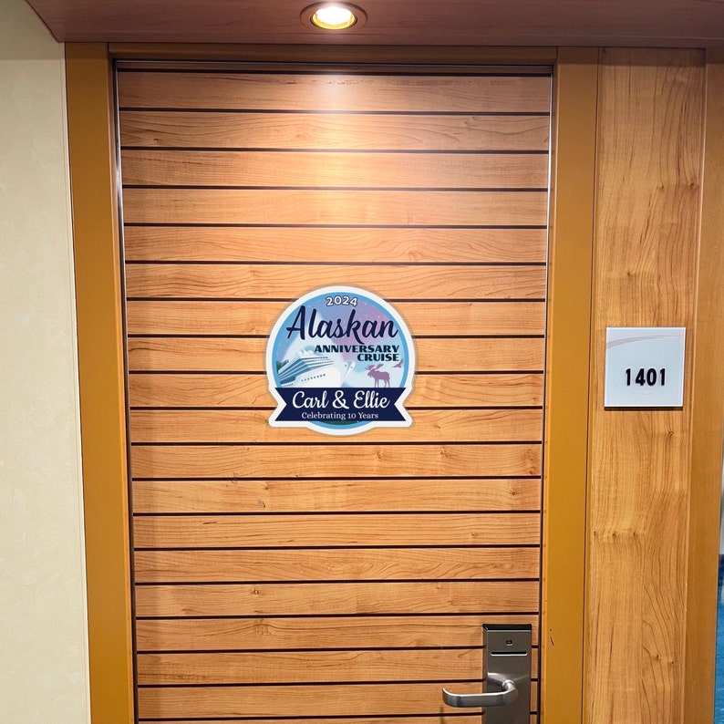 K&ouml;nnte beinhalten: Eine Holzt&uuml;r mit einem runden Aufkleber in Blau und Wei&szlig;, auf dem "2024 Alaskan Anniversary Cruise Carl & Ellie Celebrating 10 Years" steht. Neben der T&uuml;r befindet sich ein wei&szlig;es quadratisches Schild an der Wand mit der Aufschrift "1401".