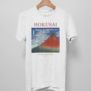 May include: A white t-shirt with a print of a famous Japanese woodblock print by Hokusai, "Fuji Mountain in Clear Weather". The print is in blue, red, and white.