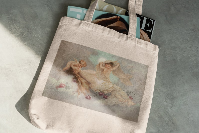 May include: A white canvas tote bag with a printed image of three cherubs in a cloudy sky. The cherubs are depicted in a soft, pastel color palette.