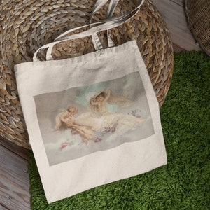 May include: A white canvas tote bag with a print of three cherubs on a cloud background. The cherubs are painted in a vintage style with soft colors.