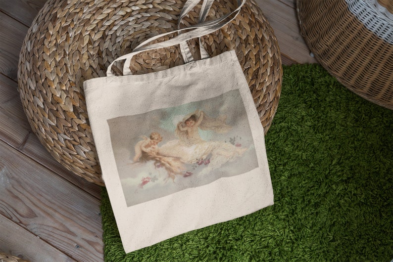 May include: A white canvas tote bag with a print of three cherubs on a cloud background. The cherubs are painted in a vintage style with soft colors.