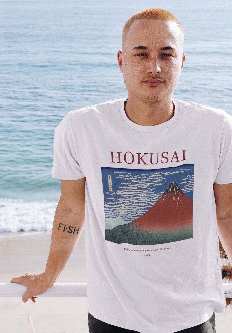 May include: White t-shirt with a red and blue graphic print of Mount Fuji and the text "HOKUSAI" and "Fuji, Mountain in Clear Weather, 1831".