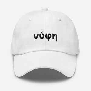 May include: A white baseball cap with a curved brim. The cap features the Greek word "νύφη" in black, centered on the front. The cap has a classic six-panel design with a button on top.