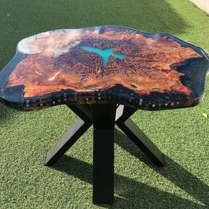 Peut inclure: Une table basse unique avec un plateau en bois à bord vif et un remplissage en résine époxy noire. Le plateau présente un motif de grain de bois naturel et une incrustation de résine bleu turquoise. La table a un piètement en métal noir avec un design en forme de croix.