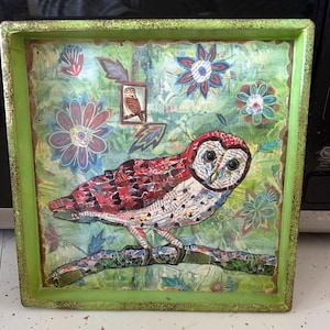 May include: Square decorative tray with a green border. The tray features a collage of an owl perched on a branch, with a background of flowers and leaves. The owl is made of paper scraps in red, white, and brown.