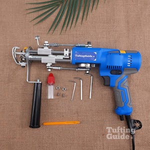May include: A blue and grey electric tufting gun with a black handle, featuring the text TuftingGuide on the side. Included are a small clear oil bottle with a red cap, two metal nuts, two screws, three L-shaped hex keys, and an orange tool.