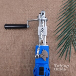 May include: A blue electric tufting machine featuring a black handle, a silver metal mechanical arm, and a white plastic component. The device includes a gear-like metal piece and a black power switch. The text Tufting Guide is visible.