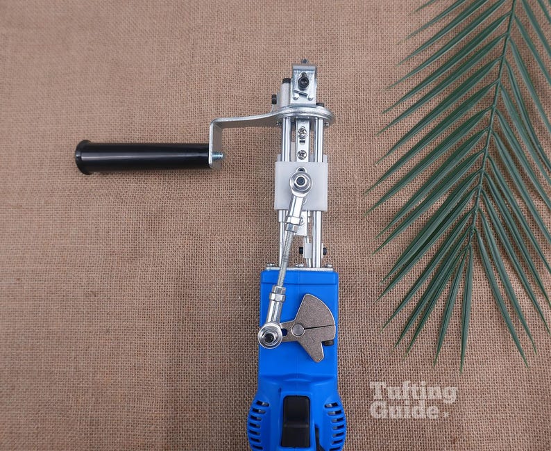 May include: A blue electric tufting machine featuring a black handle, a silver metal mechanical arm, and a white plastic component. The device includes a gear-like metal piece and a black power switch. The text Tufting Guide is visible.