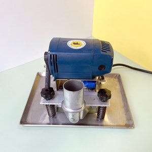 May include: A blue electric motor mounted on a silver metal base with a black knob on each side. The motor has a black cord attached to it.