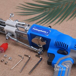 May include: A blue and grey electric tufting gun with a metal needle mechanism, featuring a TuftingGuide label. Included are a small clear oil bottle with a red cap, two metal nuts, two screws, and three L-shaped hex keys for assembly and maintenance.