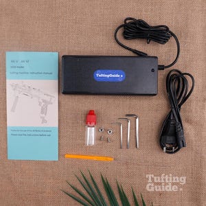 May include: A black power adapter with a TuftingGuide label, a light blue instruction manual for AK-V and AK-VI models, a small clear bottle with a red cap, two metal nuts, two screws, three L-shaped hex keys, an orange tool, and a black power cord.