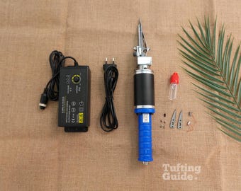 Può includere: Una pistola per tufting con impugnatura blu e corpo motore nero, accompagnata da un alimentatore nero con display digitale della tensione, un cavo di alimentazione, un piccolo flacone d'olio trasparente e vari piccoli componenti metallici di ricambio.