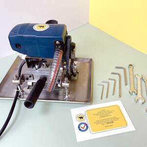 May include: A blue and silver electric glass grinder with a black hose and a set of wrenches and Allen keys. The grinder has a yellow sticker with a bear logo.