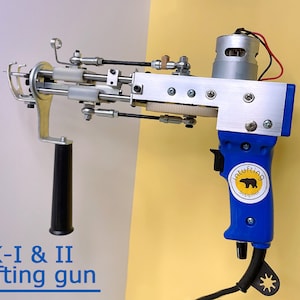 Può includere: Una pistola per tufting elettrica blu e argento con un'impugnatura nera e un'etichetta bianca che dice "Intuftig Supplies". La pistola è etichettata "AK-I & II tufting gun".