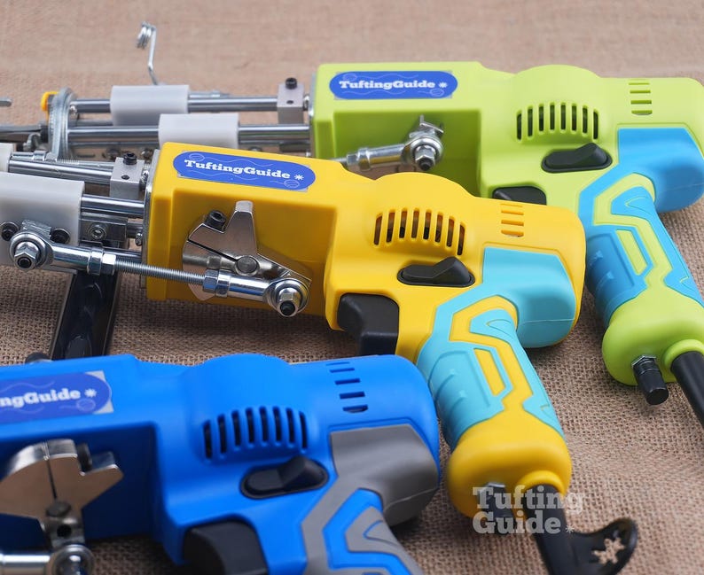 May include: Three electric tufting machines with metal needles and mechanisms. The machines feature plastic casings in lime green, yellow, and blue with light blue or grey accents. Each device displays a blue label with the text TuftingGuide.