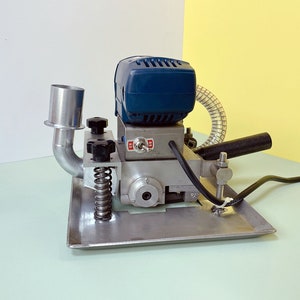 May include: A blue and silver electric sander with a dust collection hose and a spring-loaded base. The sander has a black power cord and a black handle.