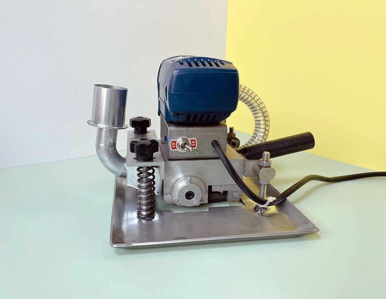 May include: A blue and silver electric sander with a dust collection hose and a spring-loaded base. The sander has a black power cord and a black handle.