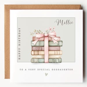 May include: A birthday card with a stack of books tied with a pink ribbon and bow. The card includes the text "Happy Birthday" and "To a very special goddaughter". The name "Millie" is written in cursive.