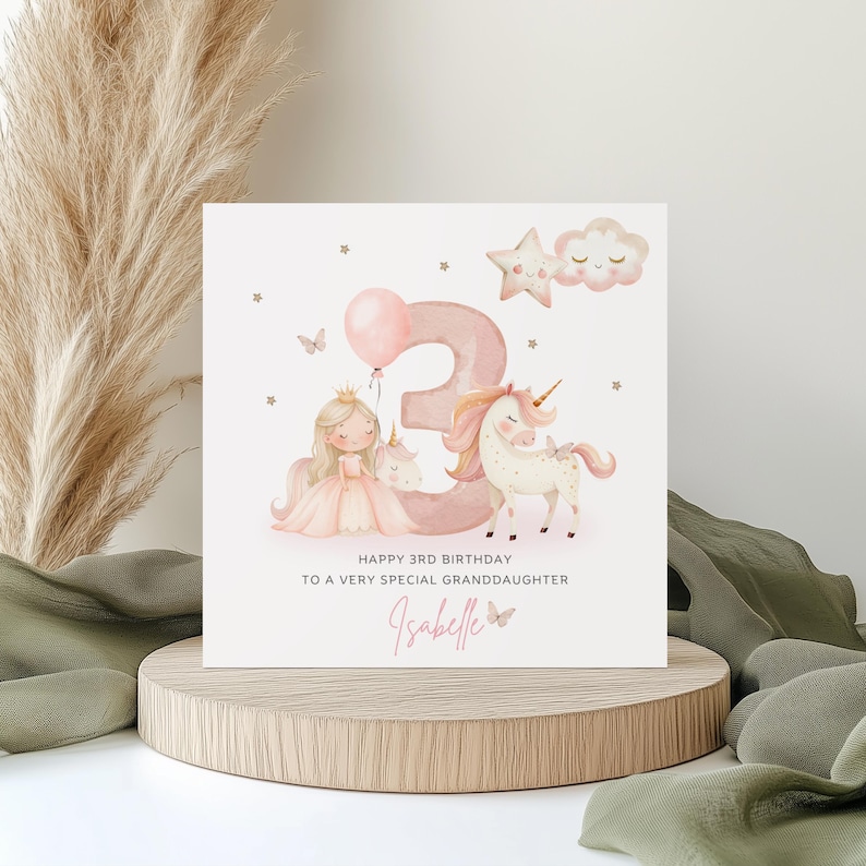 May include: A square birthday card featuring a large pink number three, a cartoon princess, and a unicorn. The text reads: HAPPY 3RD BIRTHDAY TO A VERY SPECIAL GRANDDAUGHTER, followed by the name Isabelle in pink script with a small butterfly.