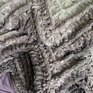 May include: A soft, gray and brown chunky knit throw blanket with a textured, woven pattern.