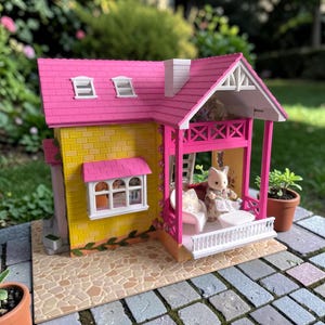 May include: A miniature dollhouse with a pink roof, yellow brick walls, and a porch. The porch has a white railing and a small table. A doll dressed in a floral print dress is seated on a white bench. The dollhouse is set on a stone patio.