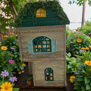 K&ouml;nnte beinhalten: Ein Miniatur-Holzhaus mit einem gr&uuml;nen, moosbedeckten Dach, einem gr&uuml;nen und gelben Fenster und hellblauen Fensterl&auml;den. Das Haus ist von bunten Blumen umgeben, darunter gelbe, rosa und lila G&auml;nsebl&uuml;mchen, was eine skurrile Gartenszene schafft.