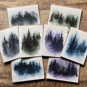 May include: Set of eight watercolor cards featuring a misty forest scene in various shades of blue, green, and purple.