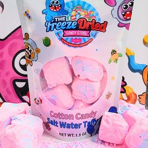 May include: A bag of pink cotton candy salt water taffy from The Freeze Dried Candy Store. The bag features cartoon characters and the text "Cotton Candy Salt Water Taffy". The net weight is 1.5 oz.