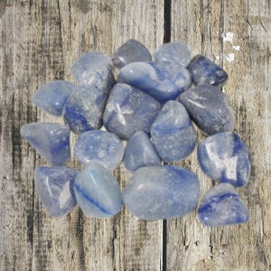 May include: A collection of smooth, light blue tumbled stones. The stones are various sizes and shapes, with a slightly cloudy appearance.