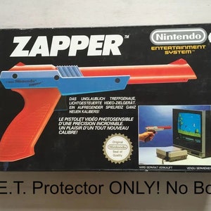 May include: A red and blue plastic Zapper light gun for the Nintendo Entertainment System. The box features the text "Zapper" and "Nintendo Entertainment System" in white lettering. The box also includes a picture of the Zapper being used to play a video game.