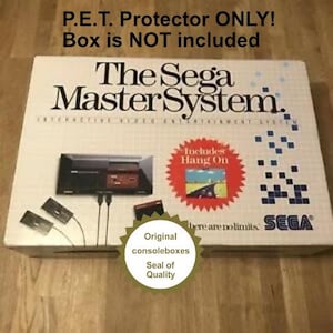 May include: A white box with a Sega Master System console inside. The box has a red and blue design with the text "The Sega Master System" and "Includes Hang On". The box also has a gold seal that says "Original consoleboxes Seal of Quality".