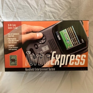 May include: A black and orange box for the Turbo Express Handheld Entertainment System. The box features a close-up of the system with a game playing on the screen. The text on the box reads "Turbo Express" and "16-Bit Color Games To Go!"