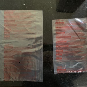 May include: Two clear plastic bags with red printed warnings and instructions. The text includes "Danger", "Attention", "Precausion", "Atention", "Peligro", "Aviso", "Achtung", "Warnung", "Attenzione", "Avvertenza", "Ostrzeżenie", "Uwaga", "Atenção", "Aviso", and "注意".