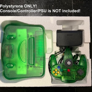 Peut inclure: Une console et une manette Nintendo 64 vertes dans un emballage en polystyrène blanc. Le texte "Polystyrène SEULEMENT ! Console/Manette/Alimentation NON incluse !" est imprimé en haut de l'emballage.