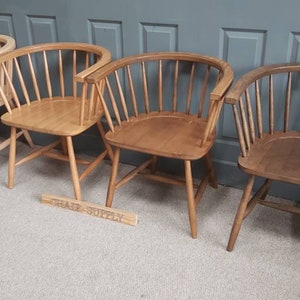 Op de afbeelding: Vier houten stoelen met een gebogen rugleuning en een latten ontwerp. De stoelen zijn in verschillende tinten bruin, van licht tot donker.
