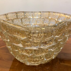 May include: A clear glass bowl with a textured, woven design. The bowl has a gold metallic finish and is perfect for serving snacks or fruit.