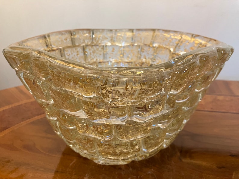 May include: A clear glass bowl with a textured, woven design. The bowl has a gold metallic finish and is perfect for serving snacks or fruit.